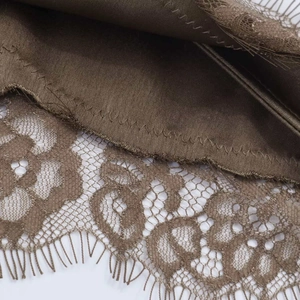 Détail du tissu satiné marron foncé avec bordure en dentelle cil et coutures délicates