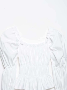 Close-up of white square neck blouse with smocked bodice and ruffled puff sleeves