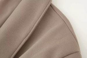 Dettaglio del rever di un cappotto di lana color cammello con cuciture rifinite