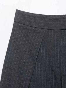 Détail du pantalon gris foncé à fines rayures montrant les plis et la texture du tissu