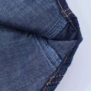 Vue détaillée des doubles coutures jaunes sur l'envers de cette chemise en denim