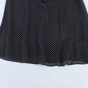 Makro-Detail des leichten schwarz-weißen Polka-Dot-Stoffs und der feinen Nähte am Kleid