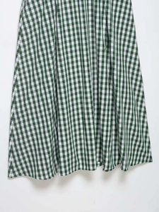 Detailed view of green and white gingham pattern fabric and hemline on summer dress