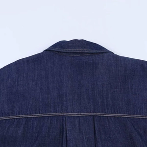 Détail d'une chemise en jean bleu foncé avec coutures contrastées et pli d'aisance