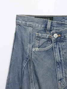 Detail of blue asymmetric high-waisted denim skirt with silver buttons and rivets