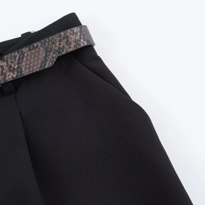 Close-up of black high-waisted tailored trousers with stylish snakeskin pattern belt detail