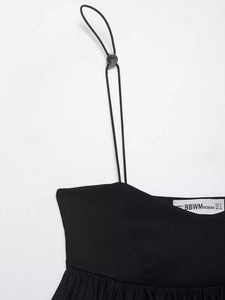 Detail of adjustable thin straps and size label on this black balloon-style top