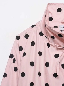 Detail of pink polka dot shirt neckline with adjustable bow tie and classic collar