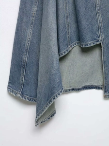 Detail of blue denim skirt featuring asymmetric hemline and premium washed fabric texture