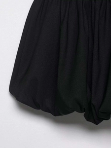 Detail of the pleated balloon hem on a black woven fabric garment with thick texture