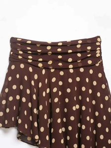Detailed view of brown polka dot skirt featuring ruffled high waist and asymmetrical hem