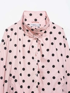 Detail of pink polka dot jacket showing high collar with drawstring and button closure