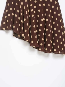 Detail of asymmetric ruffle hem on dark brown polka dot chiffon skirt with fluid layers