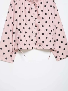 Detail of pink polka dot jacket showing drawstring hem and button-down fabric texture