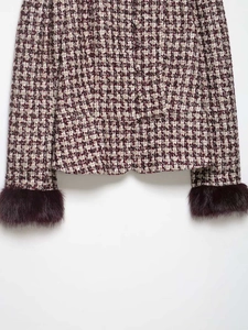 Detail of houndstooth tweed jacket featuring burgundy faux fur cuffs and matching buttons