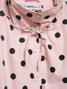 Detailed view of pink polka dot shirt featuring a drawstring collar and buttons