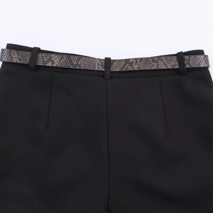 Detail of black tailored shorts with snake print leather belt and pleated stitching