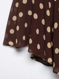 Close-up of brown chiffon polka dot fabric with elegant ruffled hemline and soft drape