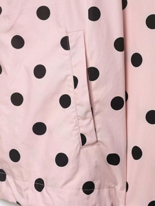 Detail shot of a pink polka dot jacket showing side pocket and high-quality stitching