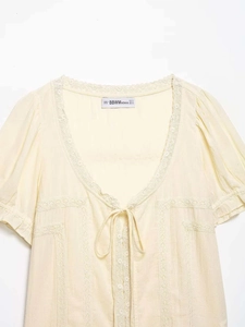 Dettaglio del pizzo sullo scollo a V e del fiocco sul camice bianco elegante