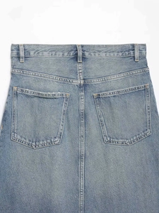 Detail view of denim skirt back pockets and high waist with washed light blue finish