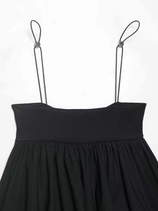 Detail of adjustable thin black shoulder strap with silver metal slider on pleated top