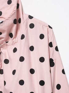 Close-up of pink long-sleeved blouse with black polka dot print and stitching details