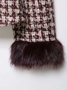 Detail of tweed jacket sleeve with purple faux fur trim and intricate woven texture