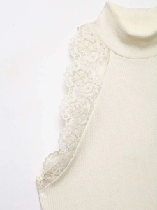 Detail shot of white knit top showing high collar and elegant lace trim on shoulder