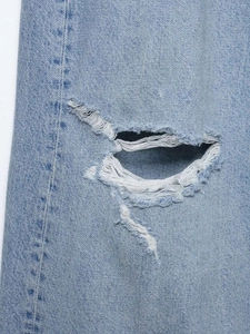 Détails de la déchirure au genou sur un jean droit délavé bleu clair style vintage