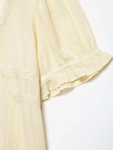 Dettaglio ravvicinato di patchwork in pizzo crema e polsini con volant sulla camicia chic