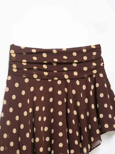 Detailed view of the pleated waistline and beige polka dots on a brown midi skirt
