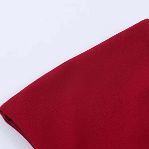 Macro shot of dark red crepe fabric with fine grainy texture and matte finish detail