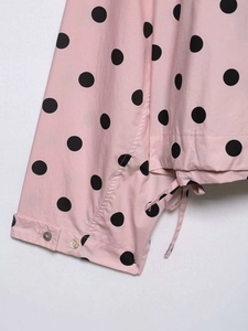 Detail of pink polka dot fabric with iridescent shell buttons and fine drawstrings