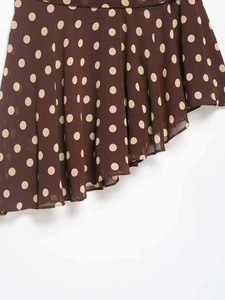 Detail of dark brown polka dot skirt featuring lightweight fabric and asymmetric hem