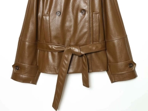 Detail of double-breasted brown PU leather jacket with waist belt and sleeve straps