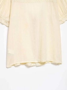 Dettaglio di una camicia bianco sporco con texture verticali e delicati accenti in pizzo