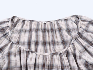 Detail of round neckline with delicate pleats and plaid woven texture on the blouse