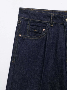 Detailed macro shot of dark blue denim jeans waist with orange stitching and metal rivets