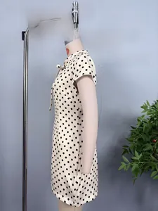Detailed side view of beige polka dot short dress featuring a bow neckline and slim fit cut