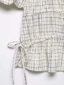 Detail of checkered top showing floral embroidery texture and adjustable side drawstring