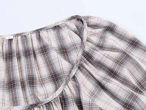 Close-up of neckline stitching and size S label on checkered pattern fabric