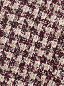 Close-up of houndstooth tweed fabric in burgundy and beige with gold metallic threads