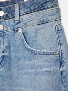 Détail d'un jean bleu clair avec une taille double unique et un design déconstruit moderne
