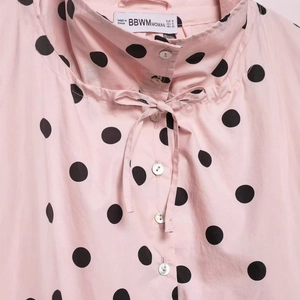 Chic pink long-sleeve blouse with black polka dots, bow tie collar, and pearl buttons