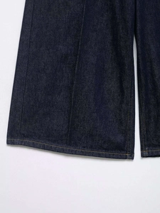 Detailed close-up showing the heavy denim fabric texture and stitching of dark blue jeans