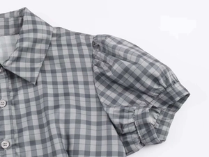 Close-up of gray and white checkered dress with puff sleeves and collared neck detailing