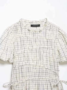 Detail of ruffled stand-up collar and black gingham fabric with floral embroidery