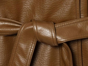 Detail of caramel leather trench coat waist with a tied belt and fine stitching work