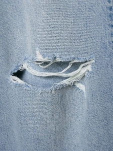 Vue macro du tissu denim bleu clair montrant des détails de déchirures et de texture